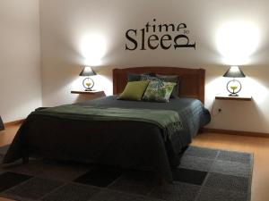 una camera da letto con un letto con un piumone verde e due lampade di Central House a Ribeira Grande