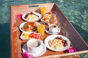 a tray of breakfast food on a wooden boat at Hôtel Bambou & Spa in Les Trois-Îlets