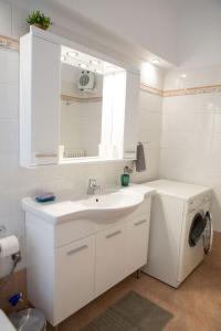 een witte badkamer met een wastafel en een wasmachine bij Athens Galatsi Spacious Modern Apartment in Athene