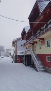 a building with a snow covered staircase next to it at Vila MDM in Straja