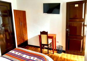 a room with a bed, chair, refrigerator and a tv at Hotel Santa Maria in Cusco