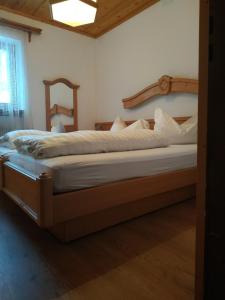 アンテルセルヴァ・ディ・メッツォにあるApartment Antholzerseeのベッドルーム1室(大型ベッド1台、木製ヘッドボード付)