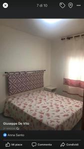 a bedroom with a bed with a red and white comforter at Casa Antony in San Teodoro +9 photos