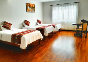 Un grupo de 4 camas en una habitación en Hotel Santa Maria, en Cusco