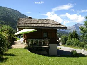 eine kleine Hütte mit einem Tisch und einem Sonnenschirm in der Unterkunft Peaceful Chalet in Les Houches with Mountain Views in Les Houches