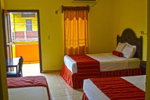 a hotel room with two beds and a window at Hotel Plaza Palmero in San Pedro Sula