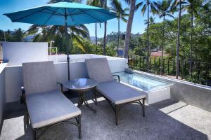 un patio con 2 sillas, una mesa y una sombrilla en Villas Robalo / Dorado Penthouses en Sayulita