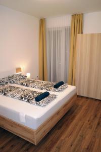 a large bed in a room with a wooden floor at Riverside Apartman with Free Parking in Győr