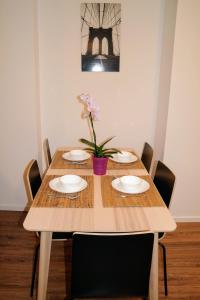 uma mesa de madeira com pratos e um vaso de flores em Riverside Apartman with Free Parking em Gyor