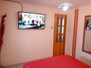 1 dormitorio con TV de pantalla plana en la pared en Departamento Arenas en Maipú