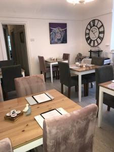 une salle à manger avec des tables, des chaises et une horloge dans l'établissement Avenue Guest House, à Blackpool