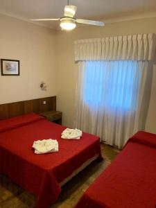 1 dormitorio con 2 camas con sábanas rojas y ventana en Hotel La Salle en Mar del Plata