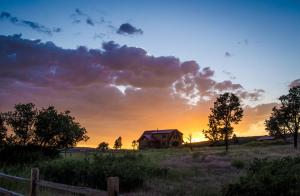 a house in a field with a sunset in the background at Zion Mountain Ranch in Mount Carmel Junction