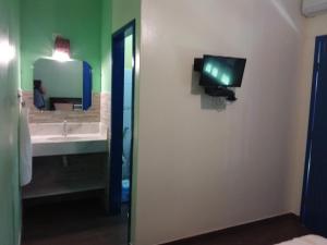 a bathroom with a sink and a tv on a wall at Pousada Das Cores in Cumuruxatiba