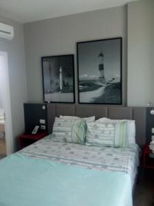 a bedroom with a bed with two pictures of a lighthouse at Aparthotel Condomínio Mondial in Salvador