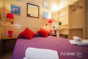 a bedroom with a bed with red pillows and a mirror at Hostal La Fontana in Madrid