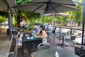 a man sitting at a table in front of a patio at Hidden Valley Holiday Park Darwin in Darwin