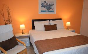 a bedroom with a bed and a chair and two lamps at Apart Hotel Terrazas de San Francisco in Piriápolis