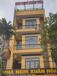 um edifício amarelo alto com um sinal em frente em Motel Xuân Hòa em Bắc Ninh
