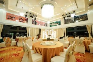 a banquet hall with a table and white chairs at Green Rose Hotel in Batam Center