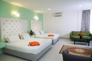 a hotel room with two beds and a couch at Akar Hotel Kampung Baru in Kuala Lumpur
