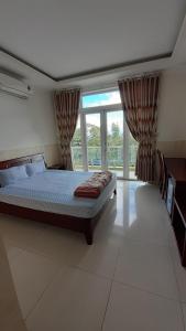 um quarto com uma cama e uma grande janela em Nhà nghỉ Bình Yên em Pleiku