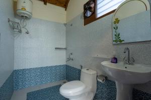 a bathroom with a white toilet and a sink at StayVista at Lake Trails with Lawn, Balcony & Lake View in Nainital +10 photos