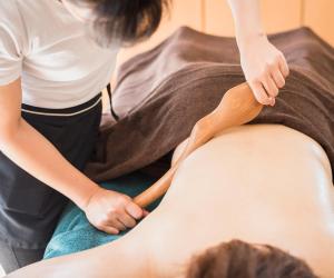 une femme recevant un massage du genou d'un patient dans l'établissement Murayama Nishiguchi Hotel, à Murayama