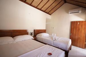 two beds in a hotel room with white sheets at Griya Nusa in Nusa Penida