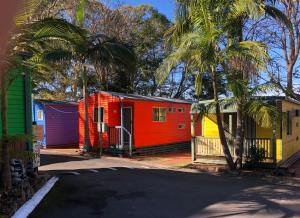 a row of colorful houses with palm trees and a street at Palm Beach Caravan Park in Sanctuary Point