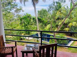 a balcony with a table and chairs and trees at Hidden Garden Tangalle in Tangalle