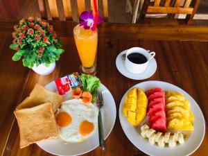 a table with two plates of breakfast food and a drink at Hatzanda Lanta Resort - SHA Extra Plus in Ko Lanta