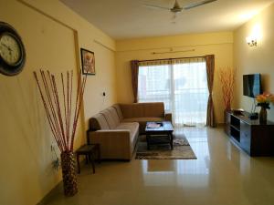 a living room with a couch and a clock on the wall at Bulande Comforts-Service Apartment In Brookfield in Bengaluru +19 photos