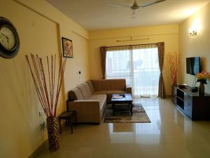 a living room with a couch and a clock on the wall at Bulande Comforts-Service Apartment In Brookfield in Bangalore