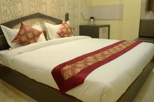 um quarto com uma cama grande com lençóis brancos e almofadas em Hotel Rahil Palace em Varanasi