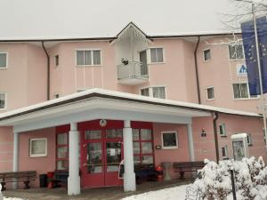 un edificio rosa con bancos delante en Jugend- und Familiengästehaus Klagenfurt en Klagenfurt