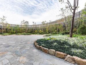 a garden with a stone patio and a tree at Hotel Hankyu RESPIRE OSAKA in Osaka