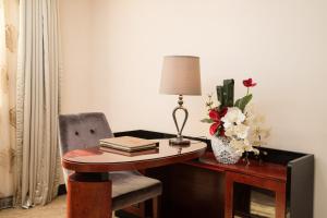 a desk with a lamp and a vase of flowers at Gorgeous Hotel in Guangzhou