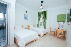 a bedroom with two beds and a table and a window at Vân Mây Homestay Hội An in Hoi An
