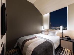 Habitación de hotel con cama y ventana grande en Hotel Hankyu RESPIRE OSAKA en Osaka