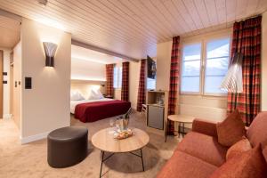 a hotel room with a couch and a bed at Hotel Kreuz&Post**** Grindelwald in Grindelwald