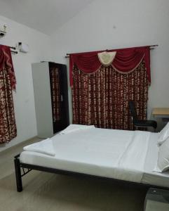 a bed in a room with a red curtain at Sai Maa Resort And Convention Centre in Puttaparthi