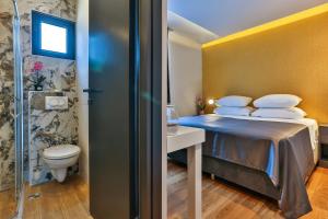 a bedroom with a bed and a bathroom with a toilet at Hotel M in Podgorica