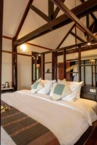a large bed with white pillows in a room at Kingfisher Ecolodge in Ban Kian-Ngông