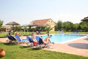un grupo de personas sentadas en sillas de césped junto a una piscina en Villagio, en Lefkada