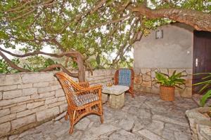 eine Terrasse mit zwei Stühlen und einer Bank unter einem Baum in der Unterkunft Vacation House Planika in Vela Luka