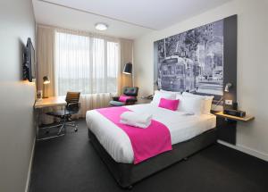 Habitación de hotel con cama grande con manta rosa en Mercure Melbourne Therry Street en Melbourne