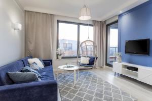 un soggiorno con divano blu e TV di Lion Apartments - NaviFlat Brabank Premium Apartment with parking a Danzica