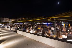 a crowd of people sitting at a restaurant at night at Dubrovnik Luxury Residence – L’Orangerie in Dubrovnik