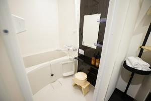 a bathroom with a tub and a toilet and a sink at EARTHMANS OSAKA-JO in Osaka